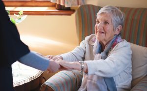 healthcare assistant helping an older person to stand