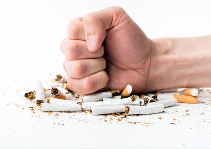 Fist pressing down on cigarettes - quit smoking