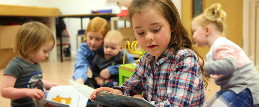 Toddlers and children happily playing and reading books.