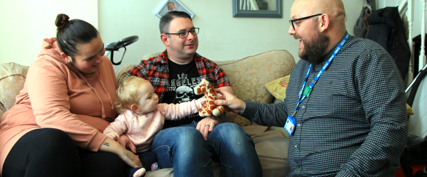 Male health visitor with mum, dad and toddler.