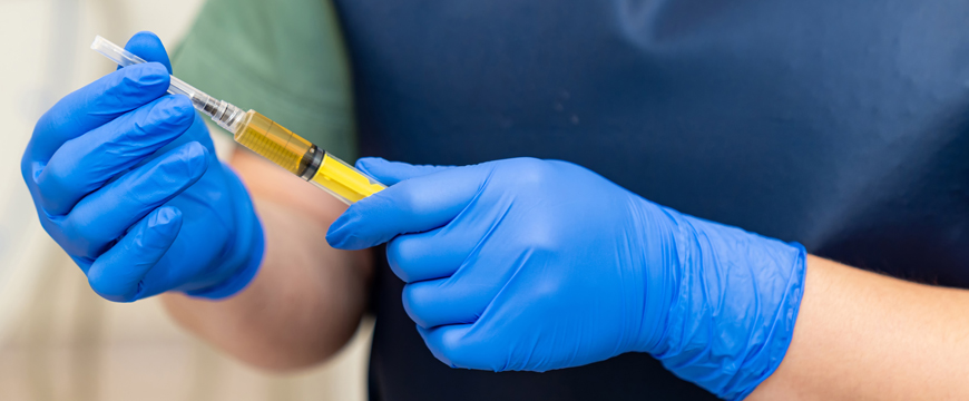 Medical professional holding a needle with a cap protecting from the sharp part of the needle