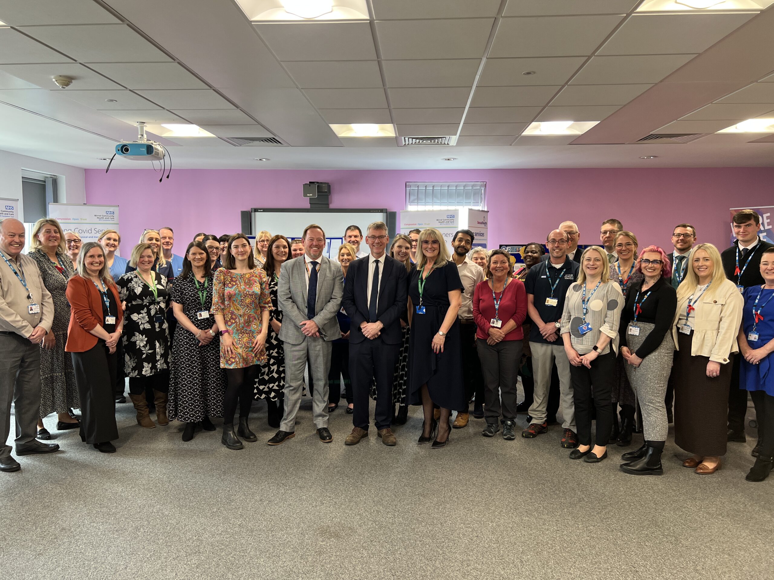 Group of NHS staff stood as a group in a large meeting room