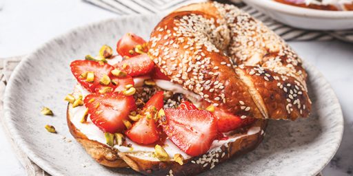 Image of a bagel with sesame seeds and strawberries. 