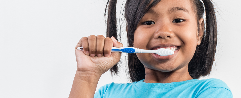 Photograph of a young girl brushing her teeth.