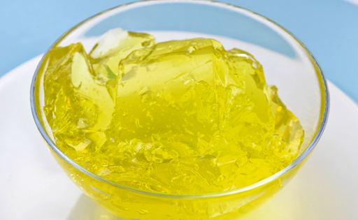 Photograph of a bowl of yellow jelly. 
