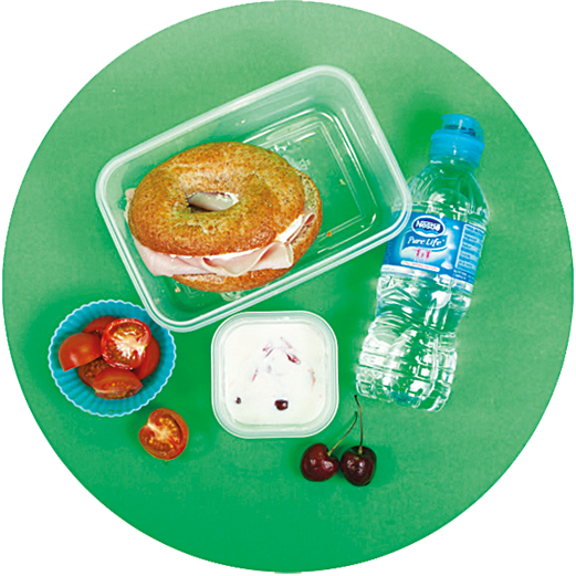 Image of a child's packed lunch which includes a wholemeal bagel with ham and soft cheese, a handful of cherry tomatoes, frozen cherries mixed with fromage frais and a bottle of water.