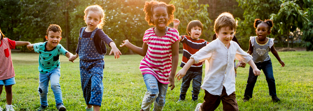Photograph of a group of children running and smiling.
