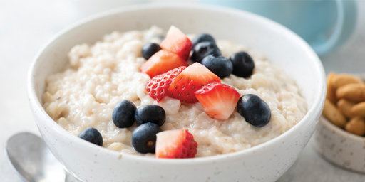 Image of a bowl of porridge with chopped strawberries and blueberries. 