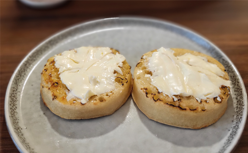 Photograph of two toasted crumpets with soft cheese.
