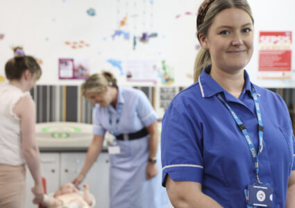 Health Visitor in uniform with colleague, and a mother and baby