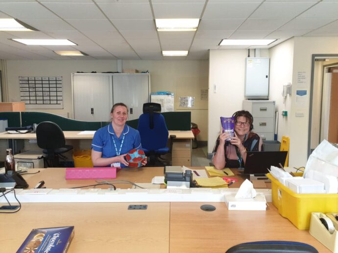 Two members of staff smiling with gifts of chocolate