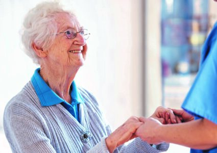 Older person holding hands with nurse