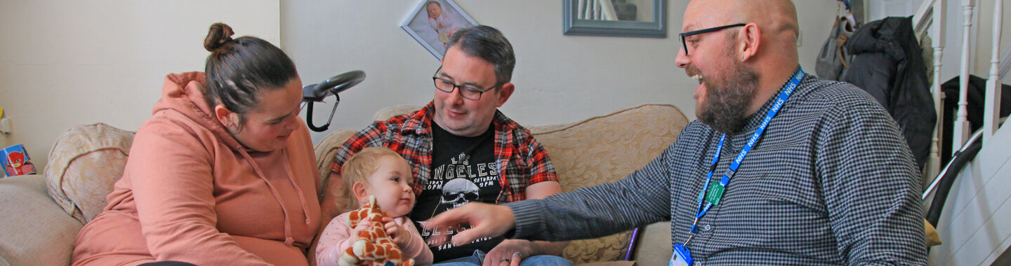 Health Visitor sat in living room with mother and father of young child