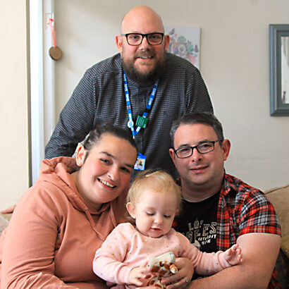 Health Visitor and little girl who is sat with her Mum and Da