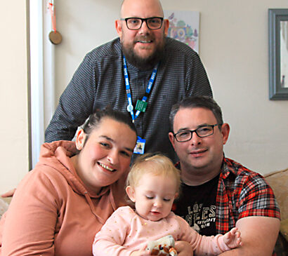 Health Visitor and little girl who is sat with her Mum and Da