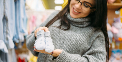 Lady holding baby socks in her and and smiling.